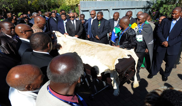 Local chiefs led by Chief Matanzima (back left with leopard print shirt) took over from the ANC to lead the body of Nelson Mandela into his home in Qunu. The casket is drapped in lion skin. Source: GCIS