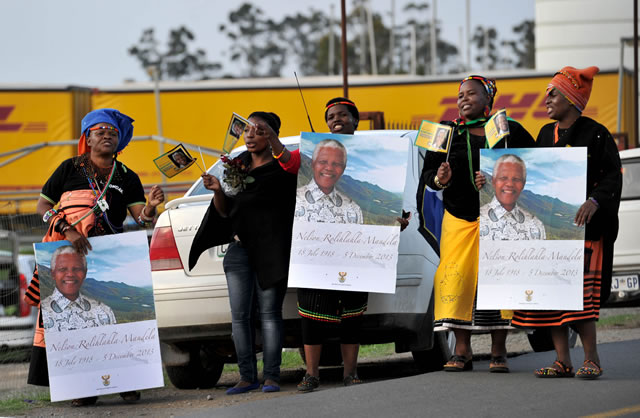 Community members singing next to the area where the procession will stop for a few seconds before reaching the Mandela home. Source: GCIS