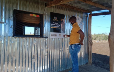 A GCIS staffer in the Eastern Cape's OR Tambo District puts up a vaccination info poster.